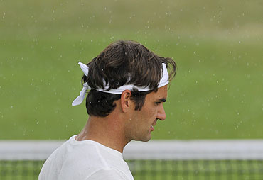 Roger Federer trains in the rain on a practice court on Sunday