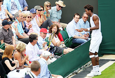 Gael Monfils retrieves his racket from the crowd during his first round match against Matthias Bachinger