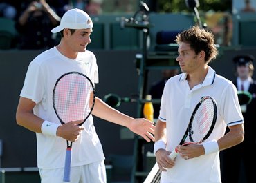 John Isner (L) and Nicolas Mahut meet up at the net before their first round match