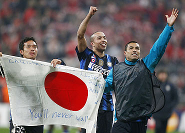 Inter Milan's Yuto Nagatomo (left) holds up a Japanese flag and celebrates with teammate Houssine Kharja (centre) after their win over Bayern Munich on Wednesday