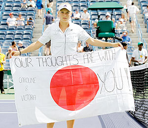 Caroline Wozniacki of Denmark holds a flag dedicated to the people of Japan after her match against Victoria Azarenka of Russia on Thursday