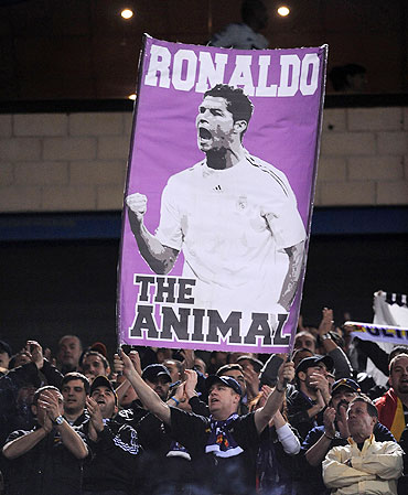 A Real Madrid fan holds up a banner of Cristiano Ronaldo before the start of the match between Atletico Madrid on Saturday