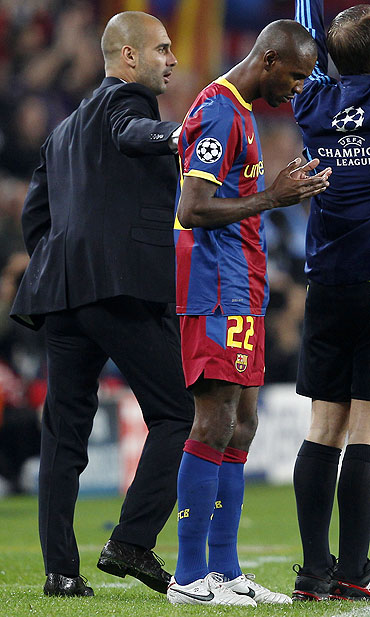 Eric Abidal says a prayer as Pep Guardiola pats him on the back before entering the pitch
