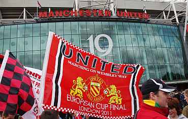 Manchester United supporters wave flags outside the stadium before their English Premier League match