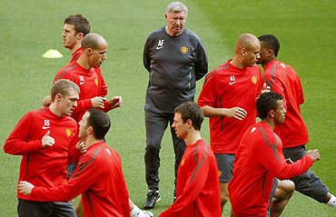 Manchester United manager Alex Ferguson (centre) watches his players go through the grind during a training session at Wembley Stadium in London on Friday