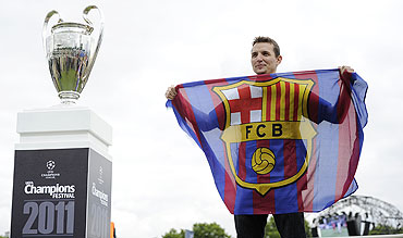 A Barcelona fan poses for a photograph next to the Champions League trophy on display at the UEFA Champions Festival in Hyde Park in London on Friday