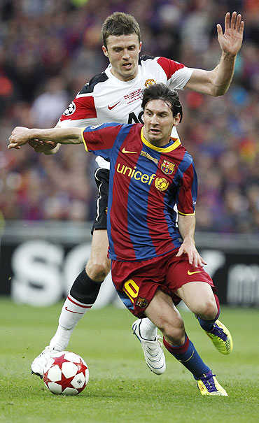 Manchester United's Michael Carrick (rear) challenges Barcelona's Lionel Messi