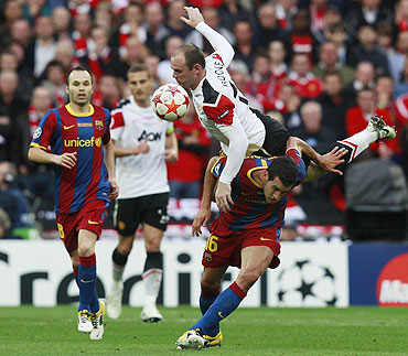 Manchester United's Wayne Rooney (top) jumps over Barcelona's Sergio Busquets as Andres Iniesta (left) looks on