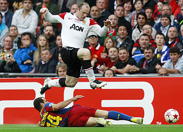 Manchester United's Wayne Rooney (top) trips over Barcelona's Javier Mascherano