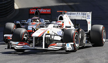 Sauber's driver Kamui Kobayashi (right) drives past McLaren's Lewis Hamilton