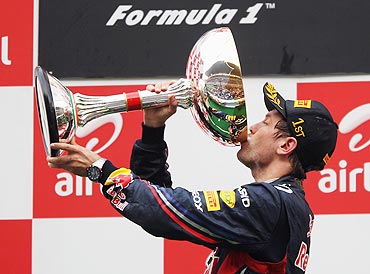 Red Bull's Sebastian Vettel drinks champagne from the trophy after winning the Indian GP