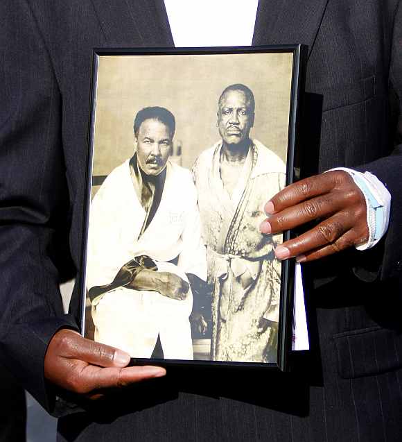 A mourner holds a photograph of boxing greats Muhammad Ali and Joe Frazier