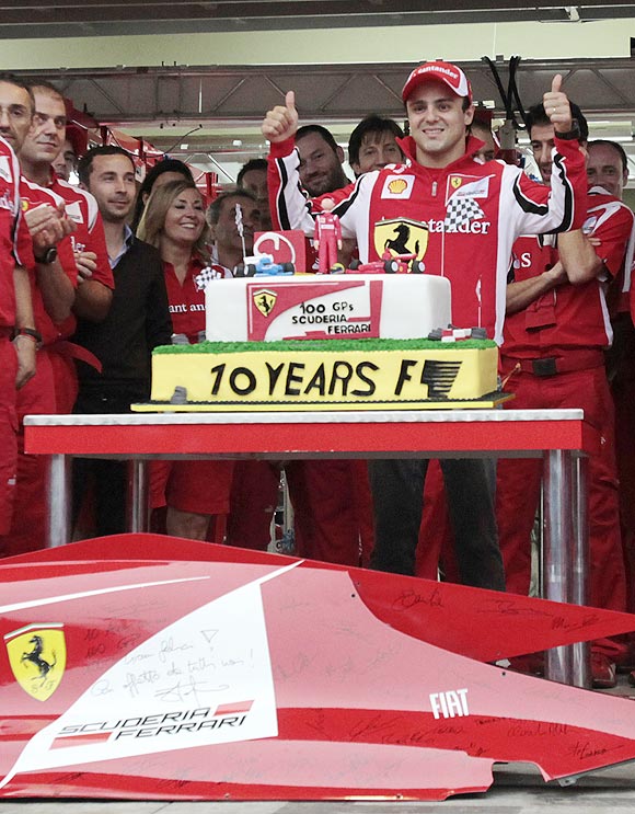 Felipe Massa poses with a cake to celebrate his 100th Formula One race for Ferrari
