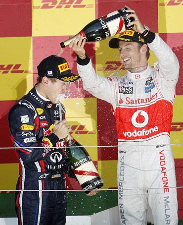 McLaren's Jenson Button (right) pours champagne over Red Bull's Sebastian Vettel as they celebrate on the podium after the Japanese GP
