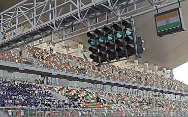 An Indian national flag flashes with a green signal as spectators watch at the Buddh International Circuit