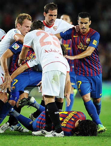 Cesc Fabreas lays on the pitch after a scuffle with Sevilla players