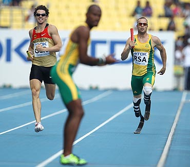 South Africa's Oscar Pistorius runs towards teammate Ofentse Mogawane during the men's 4x400 metres relay heats on Thursday