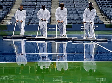 Workers dry the court at Arthur Ashe Stadium on Wednesday