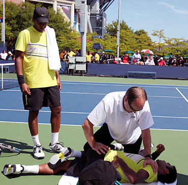 Leander Paes receives medical attention as Mahesh Bhupathi looks on during their doubles match on Thursday