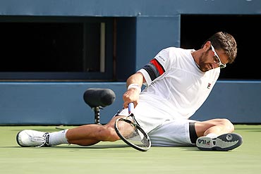 Janko Tipsarevic tries to get up after losing his balance during play against Novak Djokovic