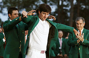 Bubba Watson of the US (centre) receives his green jacket from 2011 champion Charl Schwartzel of South Africa after the 2012 Masters Golf Tournament at the Augusta National Golf Club on Sunday