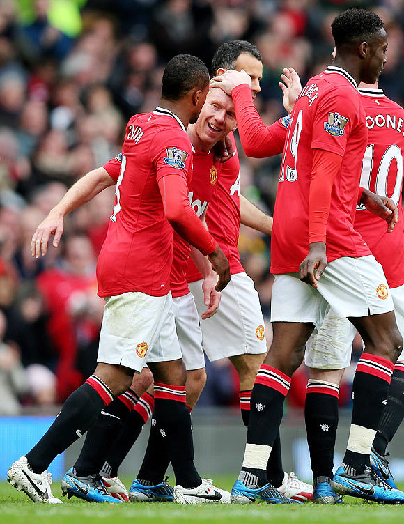 Manchester United players celebrate with Paul Scholes after the veteran midfielder struck the winner against QPR on Sunday