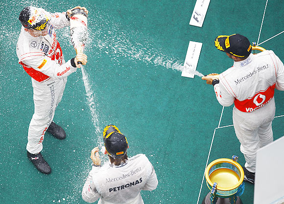 McLaren Formula One driver Jenson Button (left), team-mate Lewis Hamilton (right) and Mercedes Formula One driver Nico Rosberg spray champagne at each other