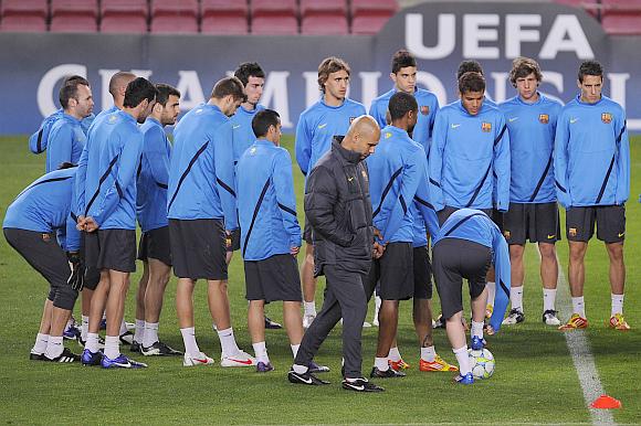 Head coach Josep Guardiola (right) of FC Barcelona walks pass his players during a training session