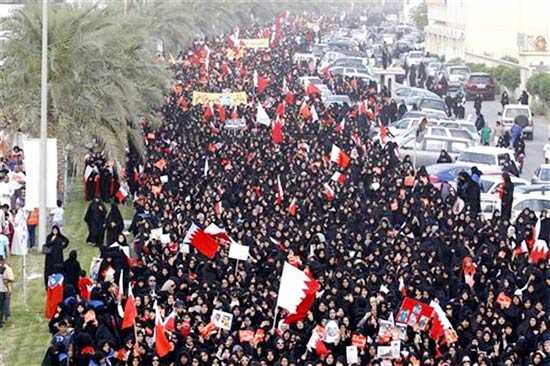 Protesters wave the Bahraini flags as they march on Budaiya highway during an anti-government protest by Bahrain's main opposition party Al Wefaq