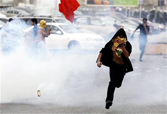 A protester runs away from tear gas released by riot police during clashes after the rally by Bahrain's main opposition party Al Wefaq in Budaiya, west of Manama