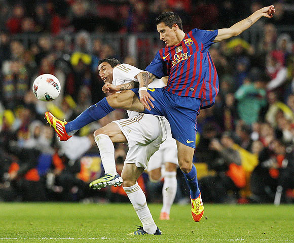 Real Madrid's Angel Di Maria (left) and Barcelona's Cristian Tello fight for possession
