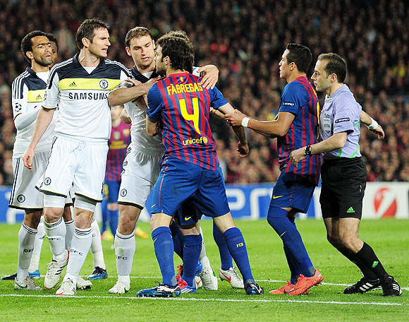 Chelsea's Frank Lampard is controlled by teammates as he confronts Barca's Cesc Fabregas