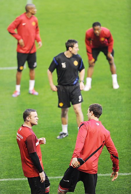 Wayne Rooney (left) of Manchester United speaks with his team-mate Jonny Evans as they excercise during a training session