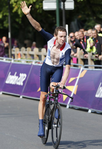 Britain's Bradley Wiggins raises his hand as he takes a victory lap after winning the men's cycling individual time trial