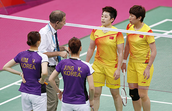 Tournament referee Torsten Berg (2nd L) speaks to players from China and South Korea during their women's doubles group play stage Group A badminton match during the London 2012 Olympic Games at the Wembley Arena on Tuesday