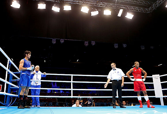 Ali Mazaheri of Iran (left) refuses to stand with the referee for his decision of a victory to Jose Gomez Larduet of Cuba during the Men's Heavy (91kg) boxing event on at the London Olympic Games on Wednesday