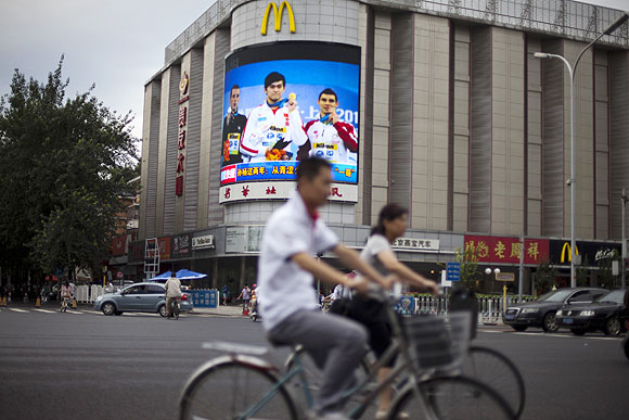 An outdoor video screen owned by Chinese state media Xinhua News Agency shows Chinese Olympic gold medalist Sun Yang (center) holding his medal at a street in Beijing on Wednesday