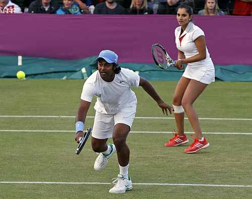 Leander Paes, left, returns a shot as he plays a mixed doubles match with playing partner Sania Mirza, right, at the All England Lawn Tennis Club at Wimbledon