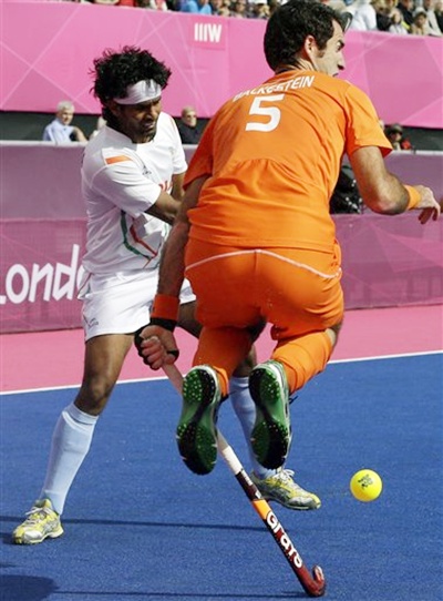 The Netherlands' Marcel Balkestein leaps out of the way as India's Shivendra Singh   moves toward the goal