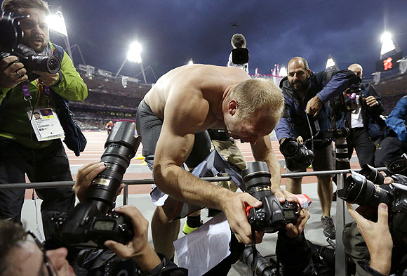Germany's Robert Harting grabs a photographer's camera as he celebrates his win in the men's discus throw on Tuesday