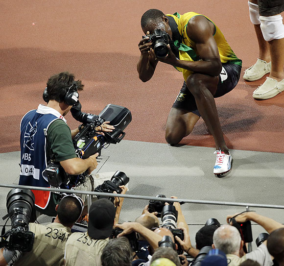 Jamaica's Usain Bolt uses a photographers camera as he takes pictures after winning the gold medal in the men's 200m on Thursday