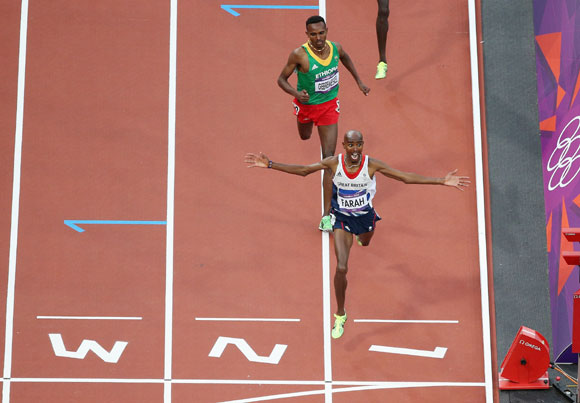Mohamed Farah of Great Britain crosses the finish line to win gold ahead of Dejen Gebremeskel of Ethiopia in the Men's 5000m Final