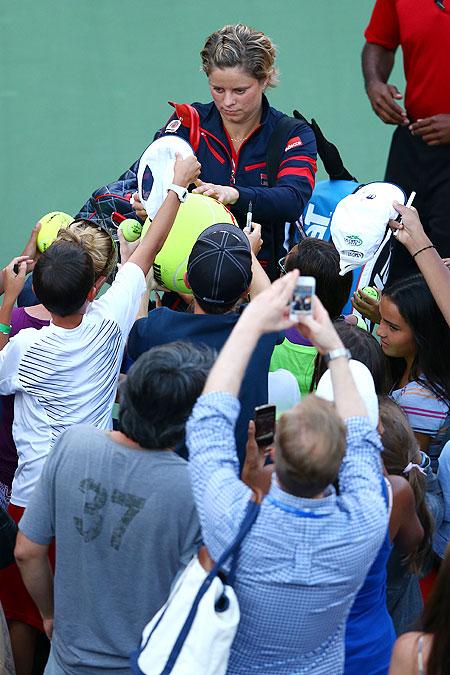 Kim Clijsters of Belgium signs autographs for fans as she leaves the court following her defeat to Laura Robson of Great Britain