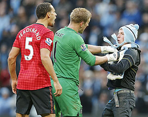 Manchester City's Joe Hart (centre) prevents supporter Matthew Stott from reaching Manchester United's Rio Ferdinand (left) after the latter was struck by an object thrown from the crowd during the Manchester derby on Sunday