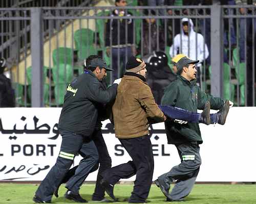 Medical personnel carry a wounded soccer fan at Port Said Stadium