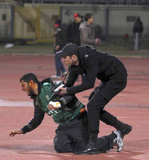 A policeman arrests an injured rioting soccer fan as chaos erupts at a soccer stadium in Port Said city