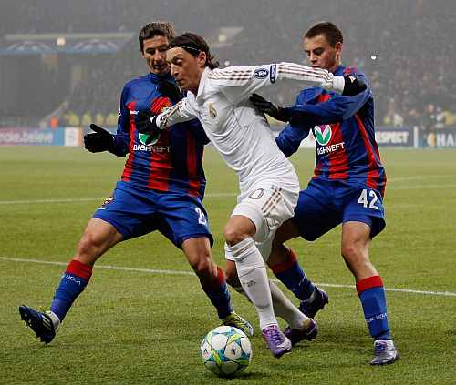 Real Madrid's Mesut Ozil fends off the challenges from CSKA Moscow players during the UEFA Champions League round of 16, first leg match at the Luzhniki Stadium
