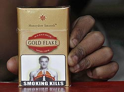 A vendor holds a cigarette pack printed with a picture bearing likeness to Chelsea's soccer player John Terry at his roadside stall in New Delhi