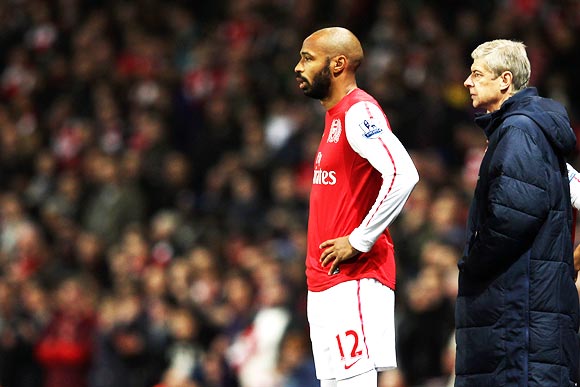 Thierry Henry prepares to come on as a substitute as manager Arsene Wenger looks on