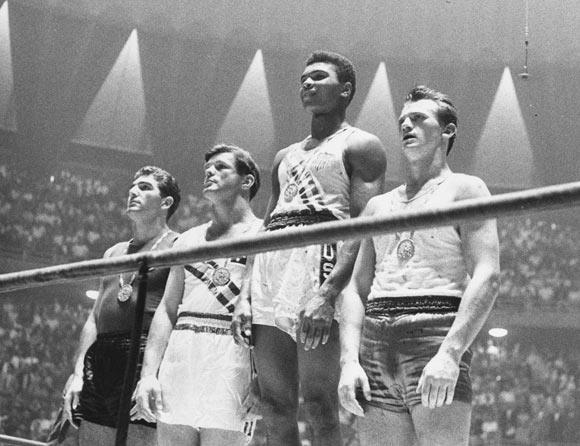 The winners of the 1960 Olympic medals for light heavyweight boxing on the winners' podium at Rome: Cassius Clay (now Muhammad Ali) (C), gold; Zbigniew Pietrzykowski of Poland (R), silver; and Giulio Saraudi (Italy) and Anthony Madigan (Australia), joint bronze